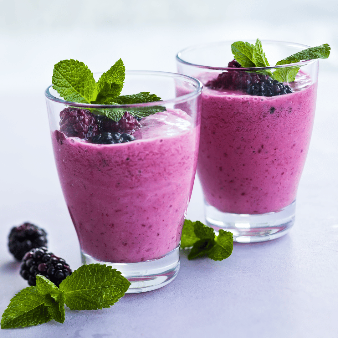 2 glasses with manuka honey berry smoothies inside garnished with mint leaves